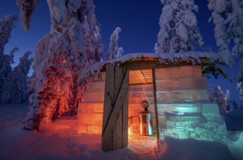 View of a cabin during winter lightened up in red and blue lights.
